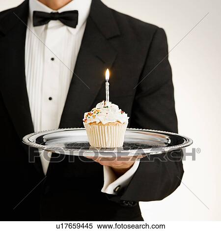 Stock Photography - Butler holding cupcake. Fotosearch