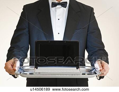 Butler holding laptop on tray View Large Photo Image Stock Photo - Butler holding laptop on tray. Fotosearch