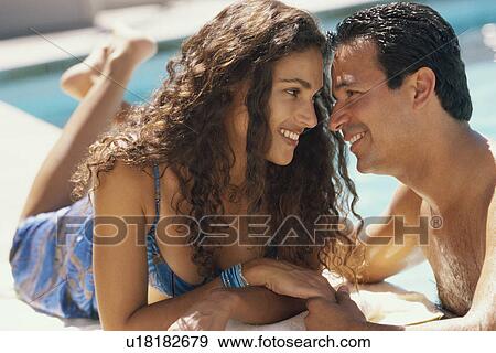 Couple relaxing by the pool View Large Photo Image Stock Photo - Couple relaxing by the pool. Fotosearch