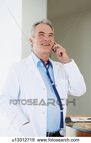 Doctor talking on phone View Large Photo Image Stock Photo - Doctor talking on phone. Fotosearch