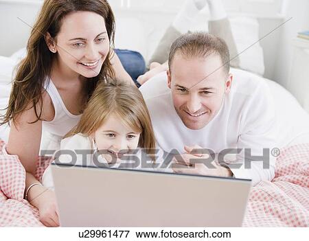Stock Photo - Family looking at laptop. Fotosearch