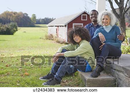 Stock Image - Family sitting on porch. Fotosearch