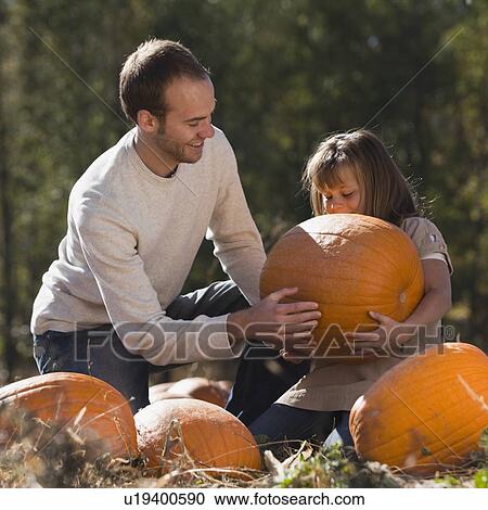 Stock Image - Father and daughter in pumpkin patch. Fotosearch