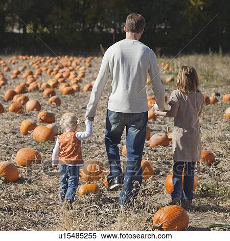 Stock Photography - Father and daughters in pumpkin patch. Fotosearch