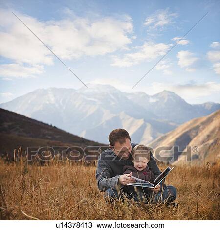 Stock Image - Father and son reading outdoors. Fotosearch
