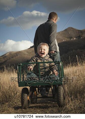 Father pulling son in wagon View Large Photo Image Picture - Father pulling son in wagon. Fotosearch