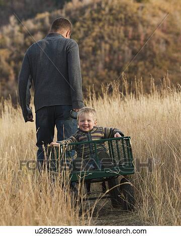 Stock Photography - Father pulling son in wagon. Fotosearch