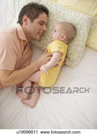 Stock Image - Father resting with baby. Fotosearch