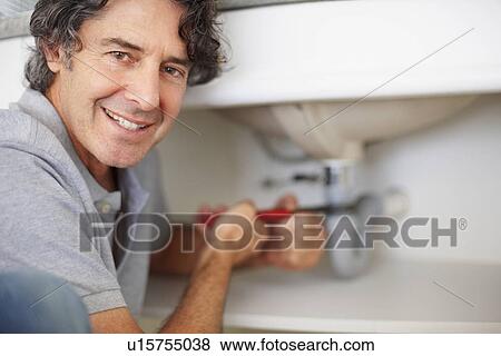 Fixing a leaky sink View Large Photo Image Stock Photo - Fixing a leaky sink. Fotosearch