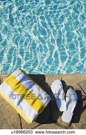 Stock Image - Flip flops and towel by the pool. Fotosearch
