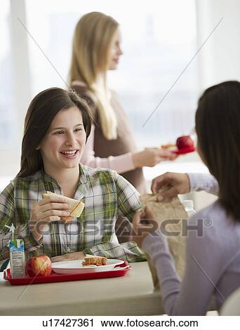 Stock Image - Friends eating in cafeteria. Fotosearch