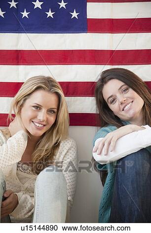 Stock Image - Friends sitting in front of American flag. Fotosearch
