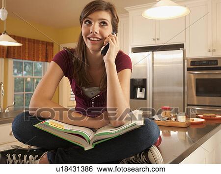 Stock Photograph - Girl sitting on kitchen counter. Fotosearch