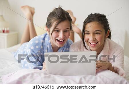 Stock Photography - Girls looking at laptop. Fotosearch