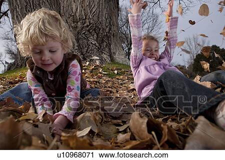 Girls playing in leaves View Large Photo Image Stock Image - Girls playing in leaves. Fotosearch