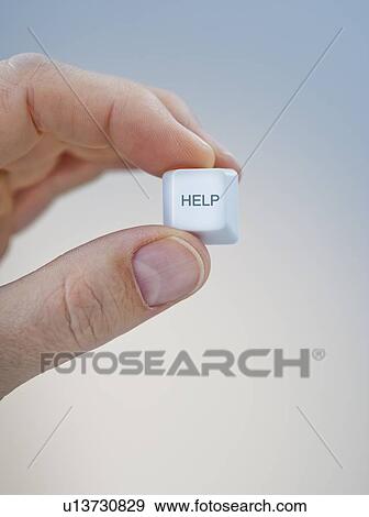 Stock Photo - Hand holding keyboard help key. Fotosearch