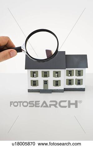 Stock Image - Looking at toy house with magnifying glass. Fotosearch