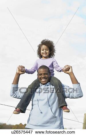 Stock Photo - Man carrying daughter on his shoulders. Fotosearch