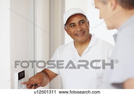 Stock Image - Man demonstrating how alarm system works. Fotosearch