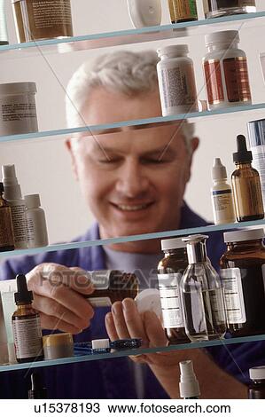 Stock Image - Man in front of medicine cabinet. Fotosearch