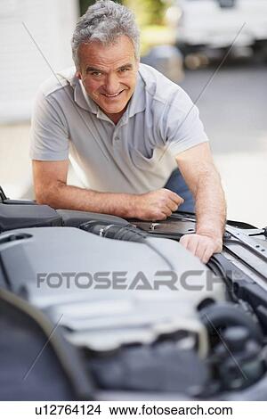 Picture - Man looking at car's engine. Fotosearch