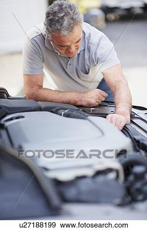 Man looking at car's engine View Large Photo Image Stock Photo - Man looking at car's engine. Fotosearch