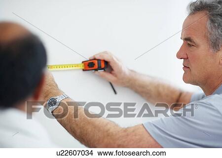 Picture - Man measuring wall. Fotosearch