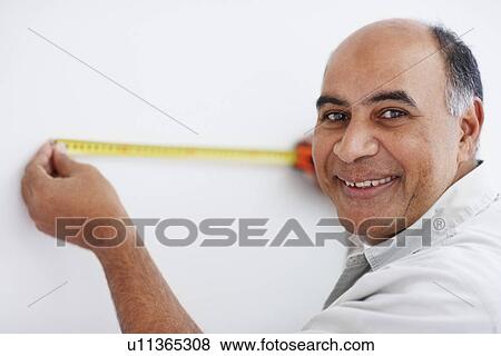 Stock Photo - Man measuring wall. Fotosearch
