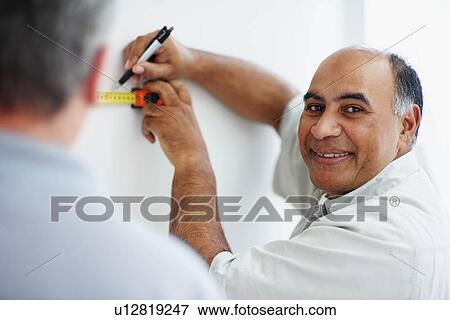 Stock Photo - Man measuring wall. Fotosearch