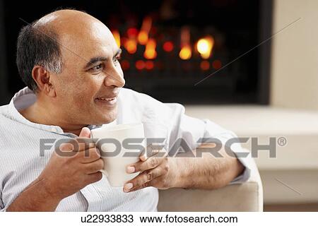 Stock Image - Man relaxing in living room. Fotosearch