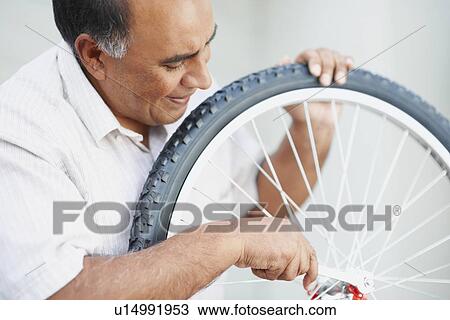 Stock Image - Man repairing bicycle. Fotosearch