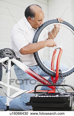 Stock Image - Man repairing bicycle. Fotosearch