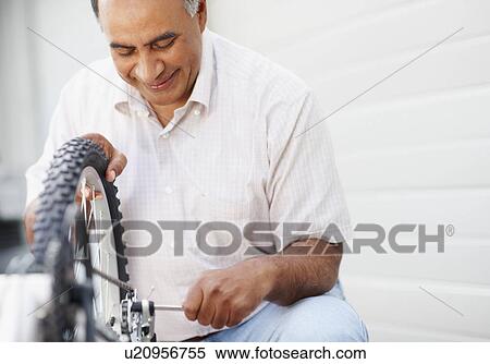 Stock Photography - Man repairing bicycle. Fotosearch