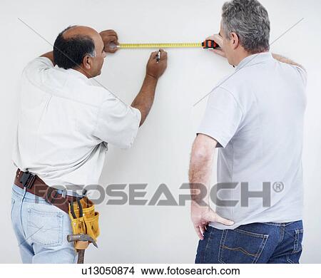 Picture - Men measuring wall. Fotosearch