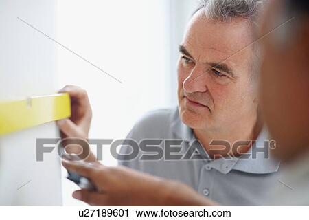 Stock Image - Men measuring wall. Fotosearch