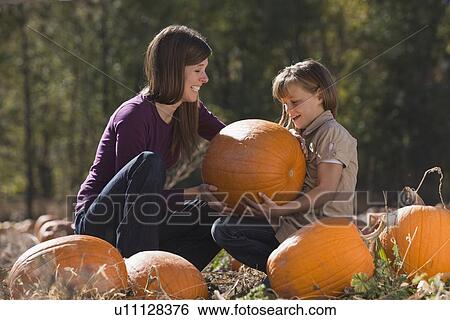 Stock Photograph - Mother and daughter in pumpkin patch. Fotosearch