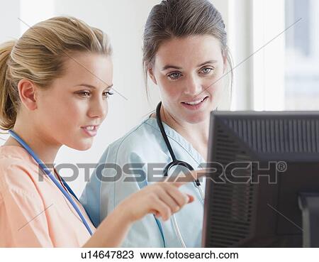 Stock Image - Nurses looking at computer. Fotosearch