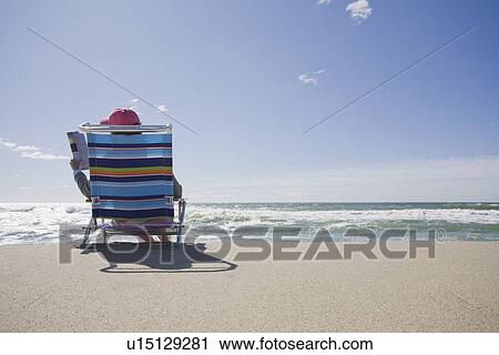 Stock Image - Reading at the beach. Fotosearch