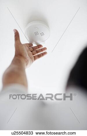 Stock Image - Testing battery in smoke detector. Fotosearch