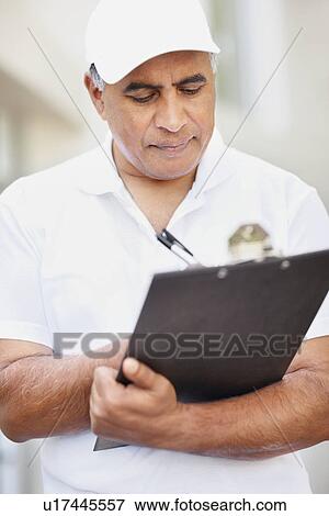 Stock Photo - Tradesman writing on clipboard. Fotosearch