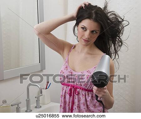 Stock Photography - Woman blow drying her hair. Fotosearch