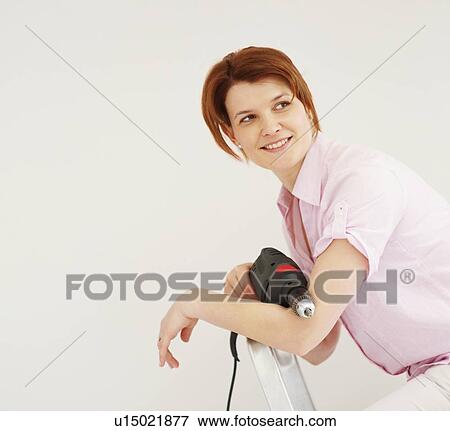 Stock Photo - Woman holding a drill. Fotosearch