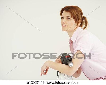 Woman holding a drill View Large Photo Image Stock Photograph - Woman holding a drill. Fotosearch