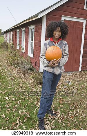 Woman holding a pumpkin View Large Photo Image Stock Photo - Woman holding a pumpkin. Fotosearch