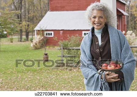 Stock Image - Woman holding bowl of apples. Fotosearch