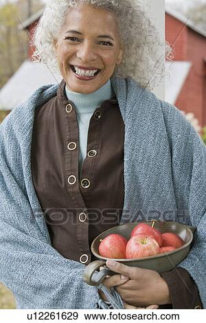 Stock Photo - Woman holding bowl of apples. Fotosearch