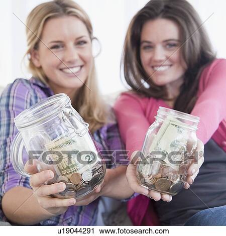 Stock Image - Woman holding jars of money. Fotosearch
