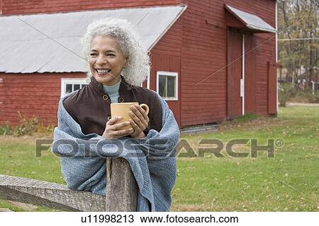 Stock Image - Woman holding mug outside. Fotosearch