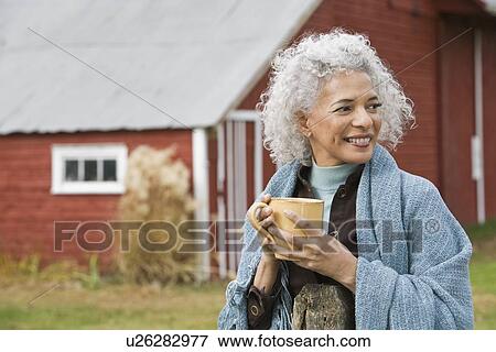 Stock Photo - Woman holding mug outside. Fotosearch