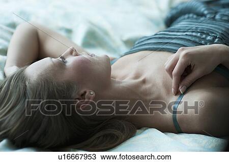 Stock Image - Woman lying down on bed. Fotosearch